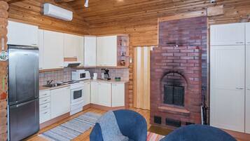 A cozy cabin-style kitchen with a brick fireplace, wooden cabinets, and a built-in stove.