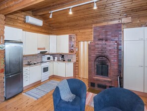 A cozy cabin-style kitchen with a brick fireplace, wooden cabinets, and a built-in stove.