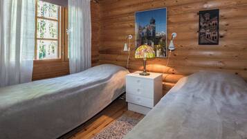 Een kamer met een slaapkamer, twee bedden, een nachtkastje en een lamp.