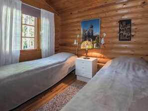 A cabin room with two beds, a nightstand, and a lamp.