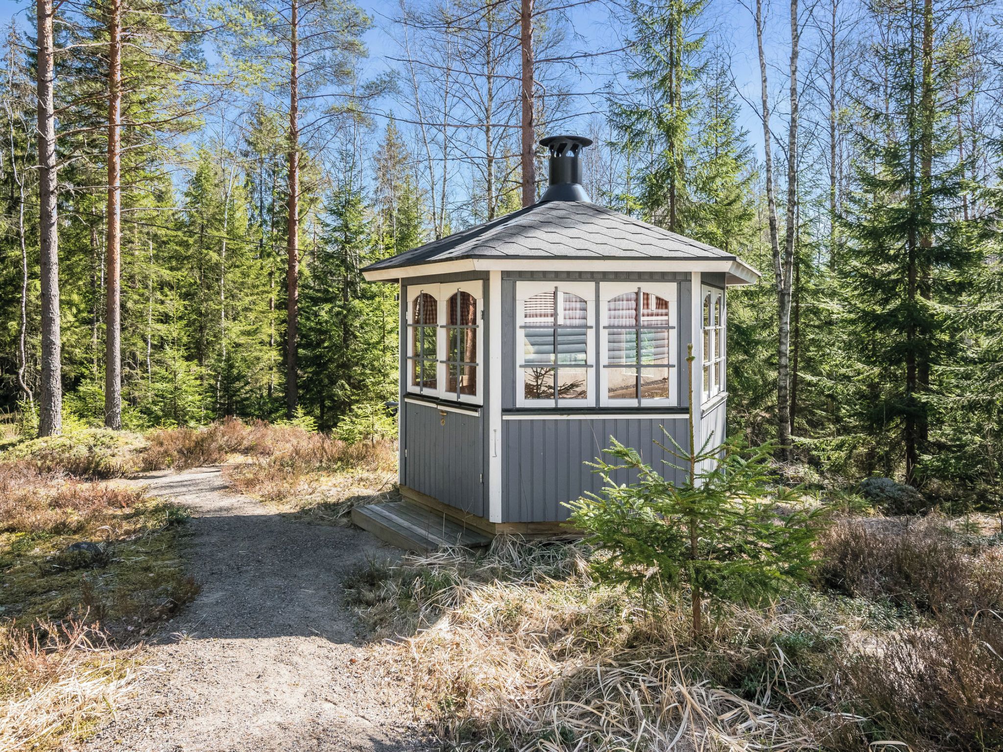 A small cabin with a single window and a chimney, surrounded by a forest.