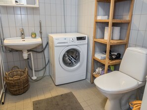 Ein kleines Badezimmer mit Waschmaschine, Waschbecken und Toilette.