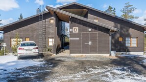 Un bâtiment moderne à deux étages, doté d’une entrée de garage, avec une voiture garée à l’extérieur et un ciel dégagé.
