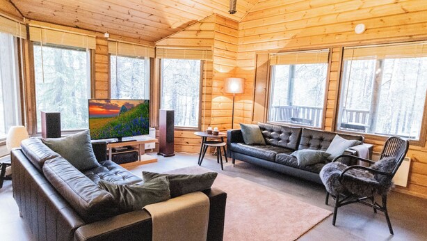Un acogedor interior de cabaña de madera con un sofá, un televisor y un comedor.