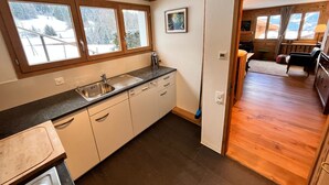 A kitchen with a sink, cabinets, and a window overlooking a snowy landscape.