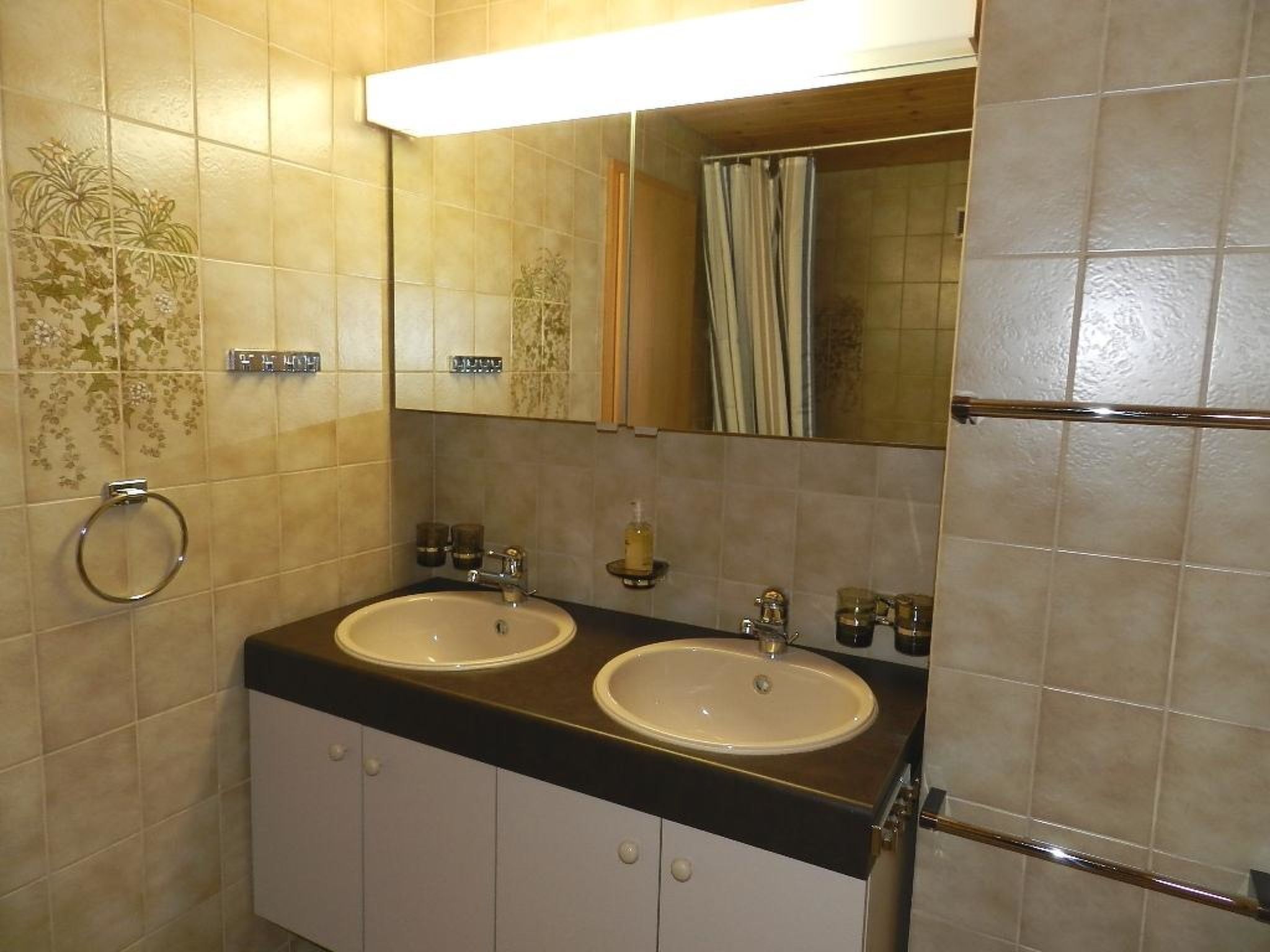 Une salle de bain avec deux lavabos, un miroir et un porte-serviettes.