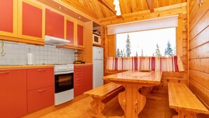 A compact kitchen with wooden cabinets, a stove, and a window with a view of trees.