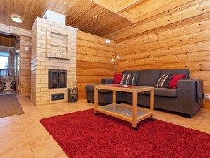 A cozy room with a fireplace, a sofa, a coffee table, and a red rug.