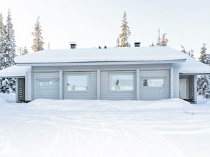 A two-story house with a covered porch, surrounded by snow-covered trees.