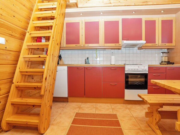 A kitchen with wooden cabinets, a stove, a sink, and a wooden ladder.
