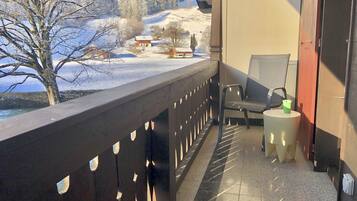 Un balcon donnant sur un paysage enneigé, avec une chaise et une petite table.