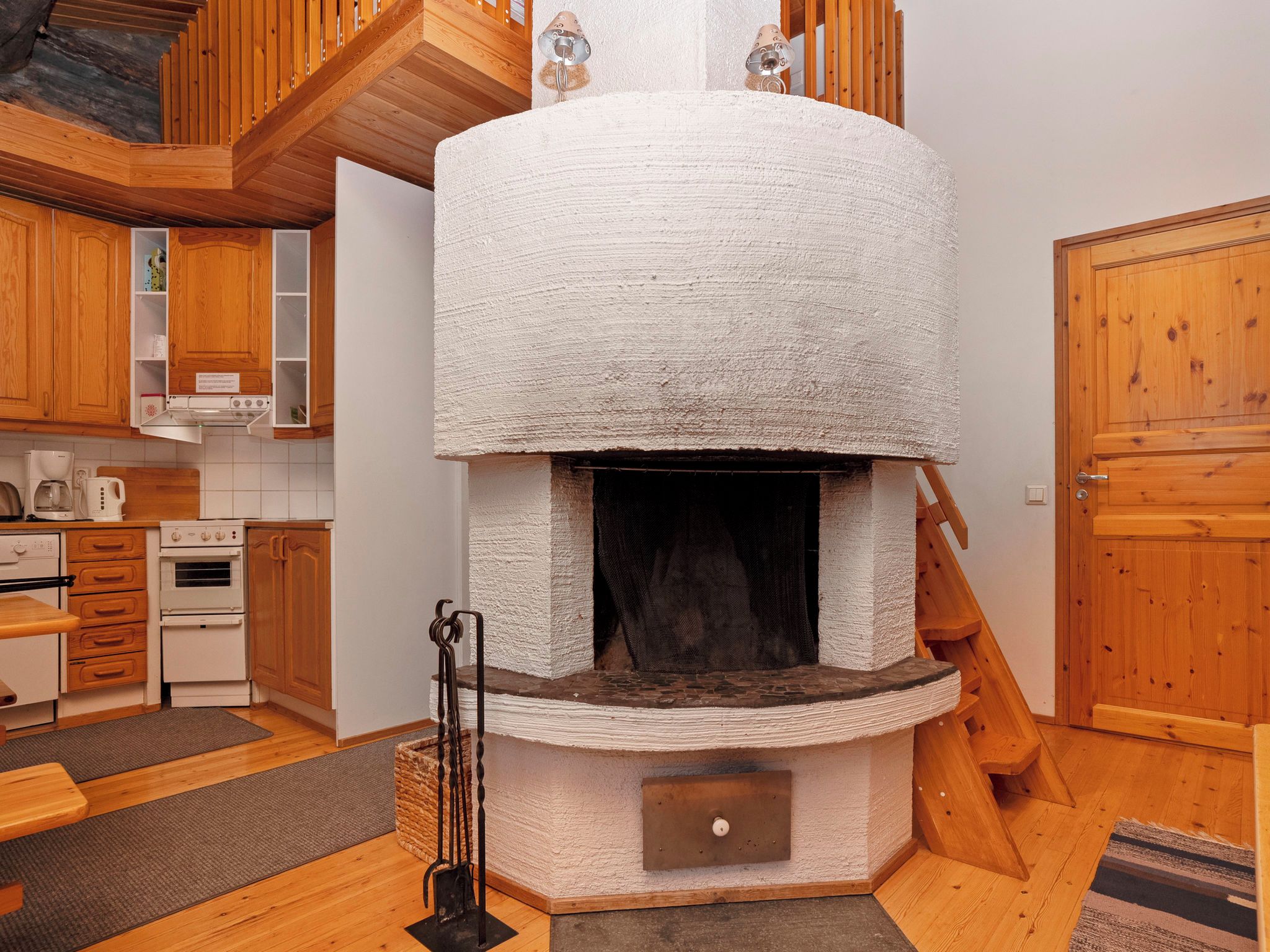 A rustic kitchen with wooden cabinets, a built-in oven, and a stone fireplace.