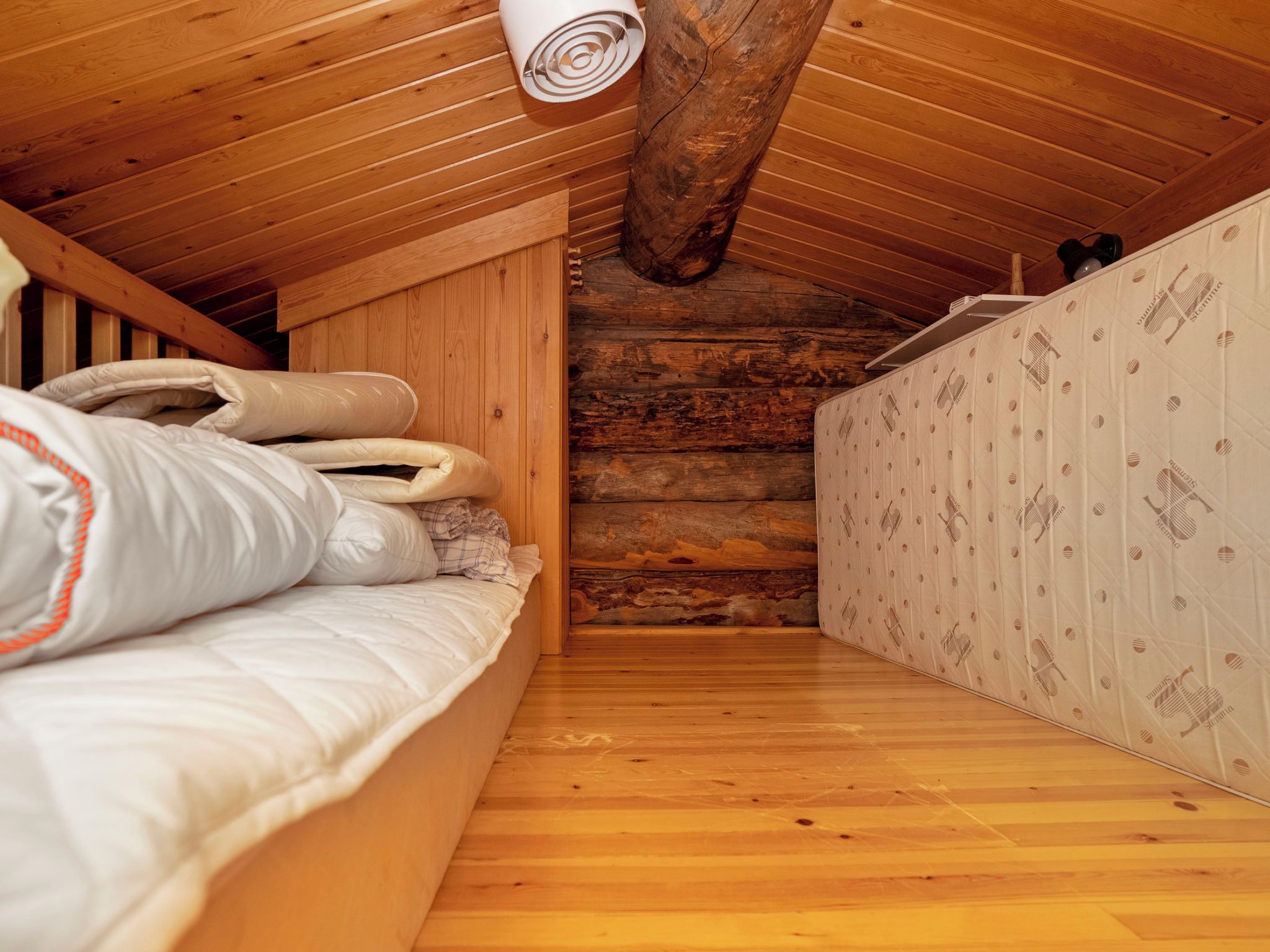 Un interior de madera con una cama litera, un colchón y una pared con estampado.