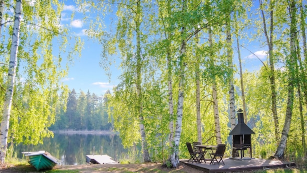 Un chalet au bord du lac, doté d’une terrasse, de meubles d’extérieur et d’une cheminée.