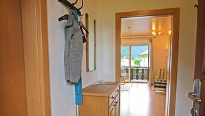 Un couloir menant à un balcon d’où l’on peut admirer des maisons et une montagne.