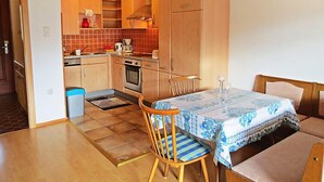 Une cuisine de taille réduite, dotée de meubles en bois, d’une cuisinière et d’un coin repas avec une table et des chaises.