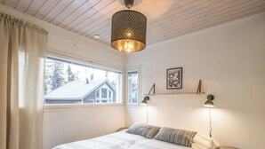 Une chambre à coucher avec un lit, une fenêtre, un luminaire suspendu et une table de chevet.