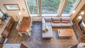 Un intérieur moderne comprenant un coin repas, un canapé et de grandes fenêtres donnant sur l’extérieur.