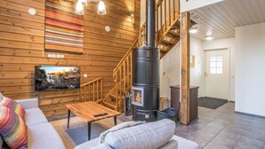 Un salon chaleureux avec une cheminée, des murs en bois, un escalier et un téléviseur.