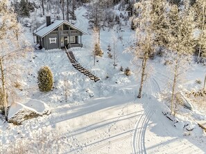 A wooden cabin with a porch, surrounded by snow-covered trees and a clear path leading to it. - Eteläranta by Interhome (Joutsa)