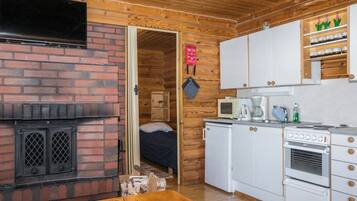 A compact kitchen with a brick fireplace, white cabinets, and a microwave.