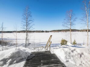 A wooden dock leading into a snowy landscape with leafless trees and a clear blue sky. - Eteläranta by Interhome (Joutsa)