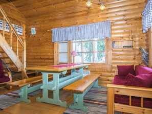 A wooden cabin interior with a dining table, benches, a sofa, and a staircase. - Eteläranta by Interhome (Joutsa)