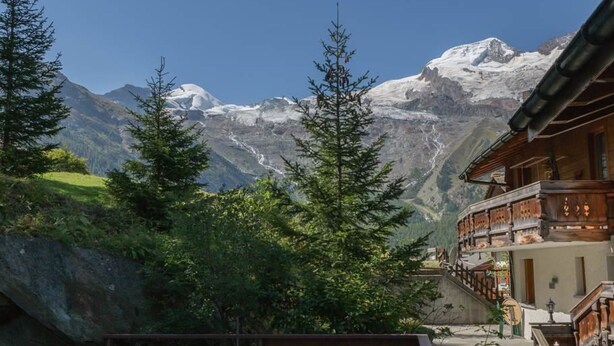 A mountain lodge with a wooden balcony overlooking a snowy mountain range. - Bergfink by Interhome (Saas-Fee)