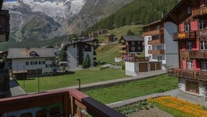 A mountain village with traditional wooden buildings, a clear view of snow-capped peaks, and a balcony with flowers. - Bergfink by Interhome (Saas-Fee)