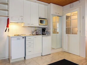 A compact kitchen with white cabinets, a microwave, a coffee maker, and a dishwasher. - Moonlight 201 by Interhome (Kittilä)
