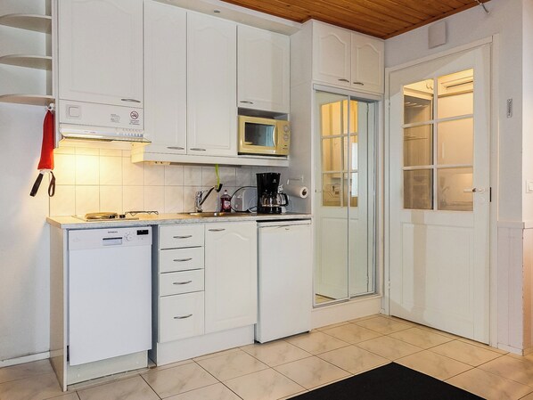 A compact kitchen with white cabinets, a microwave, a coffee maker, and a dishwasher.