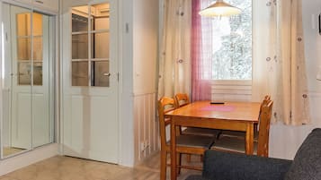 Huone, jossa on ruokapöytä, tuoleja, sohva, ikkuna verhoilla ja ovi, jossa on lasiruutu.