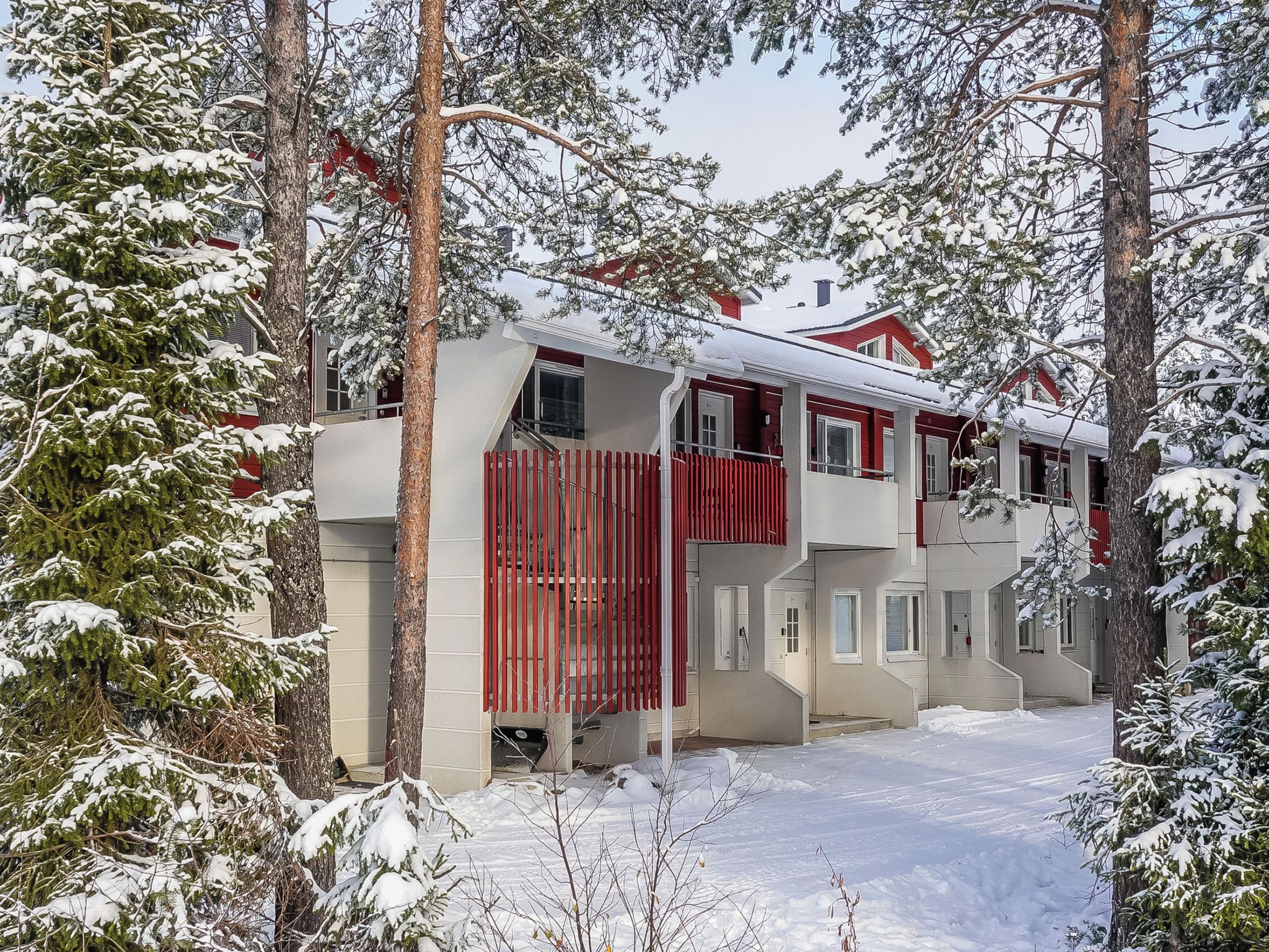 Ein zweistöckiges Gebäude mit roter Fassade, umgeben von schneebedeckten Bäumen.