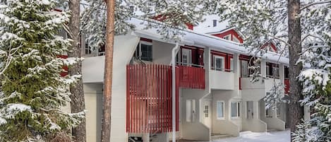 Ein zweistöckiges Gebäude mit roter Fassade, umgeben von schneebedeckten Bäumen.