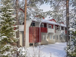 A two-story building with a red exterior, surrounded by snow-covered trees. - Moonlight 201 by Interhome (Kittilä)