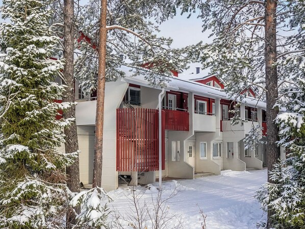 A two-story building with a red exterior, surrounded by snow-covered trees.