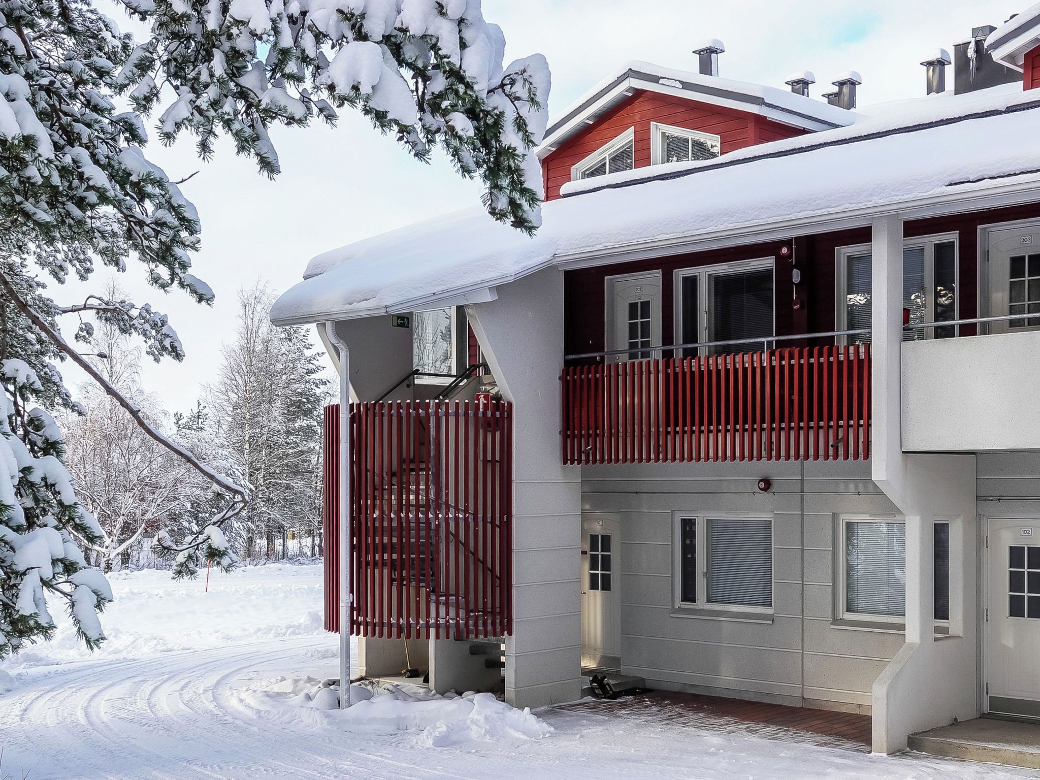 A two-story building with a red balcony, snow-covered surroundings, and a clear sky.