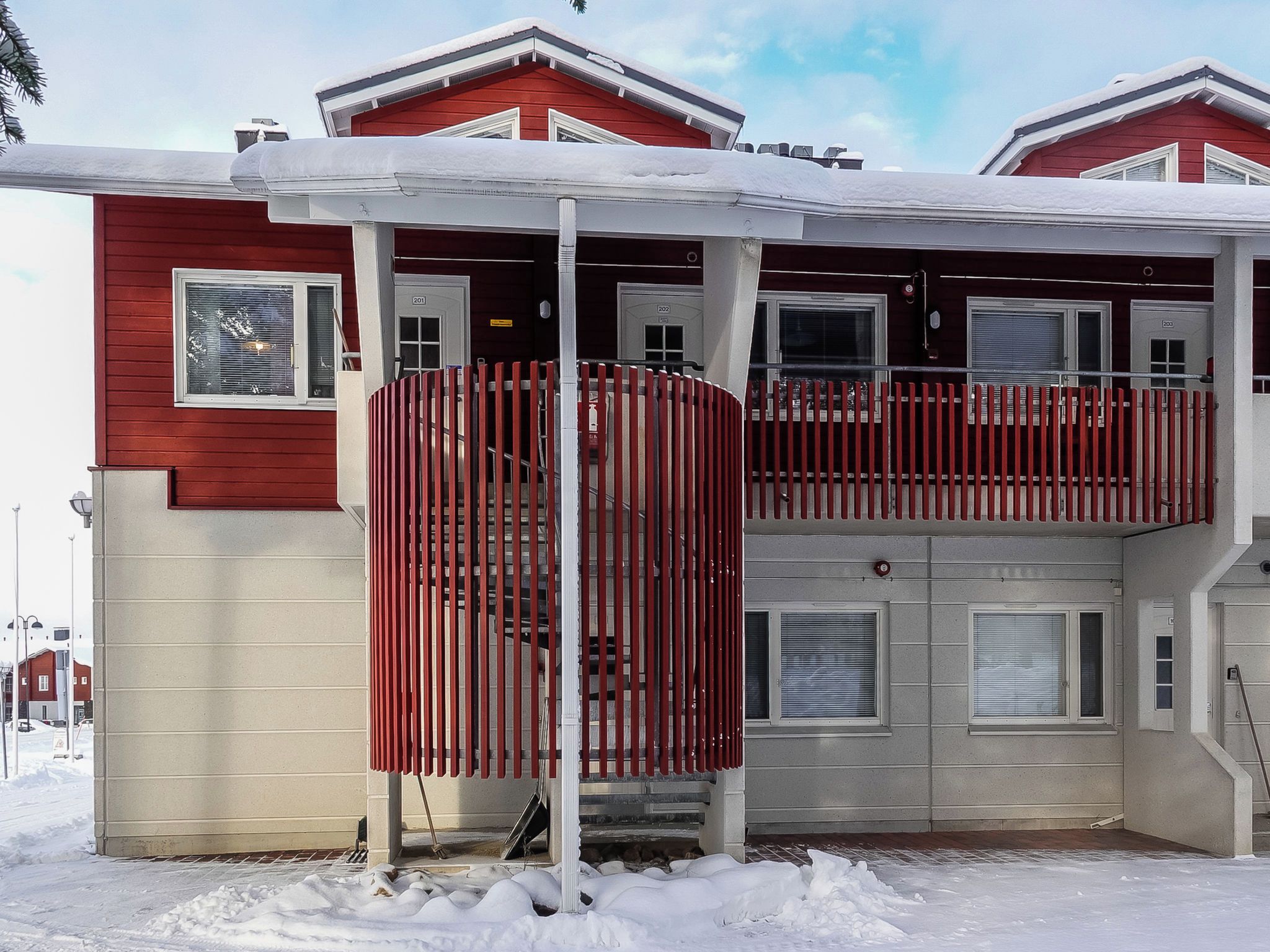 A two-story building with a red exterior and a covered entrance area.