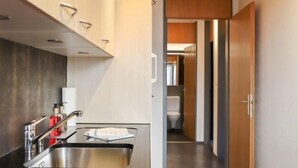 A modern kitchen with a stainless steel sink, a range hood, and a countertop with a dish rack.