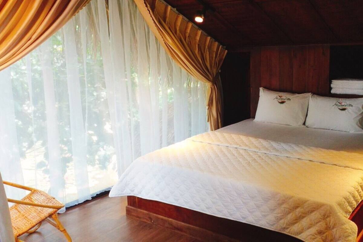A bedroom with a bed, curtains, and a chair.