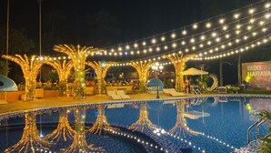 A pool area with string lights and lounge chairs. - May Tropicall Villas (Hanoi)
