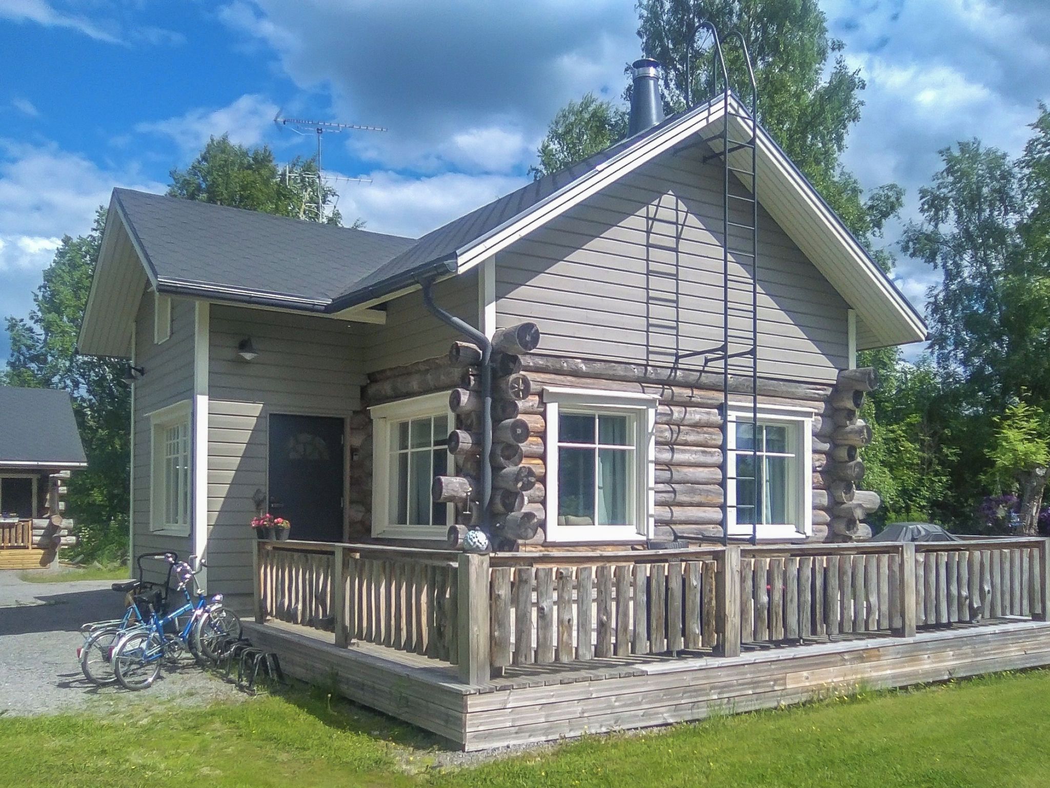 Hirsihökkelissä on kuisti, savupiippu ja sen ulkopuolella on pysäköitynä polkupyörä.