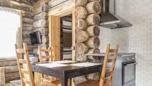 A rustic wooden dining area with a stone wall, a television, and a modern oven.