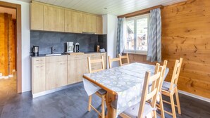 Una cocina moderna con armarios de madera, una mesa de comedor con sillas y una ventana con cortinas.