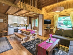 A cozy cabin interior with a wooden dining table, a sofa, a television, and a kitchen area. - Merenneito by Interhome (Pöytyä)