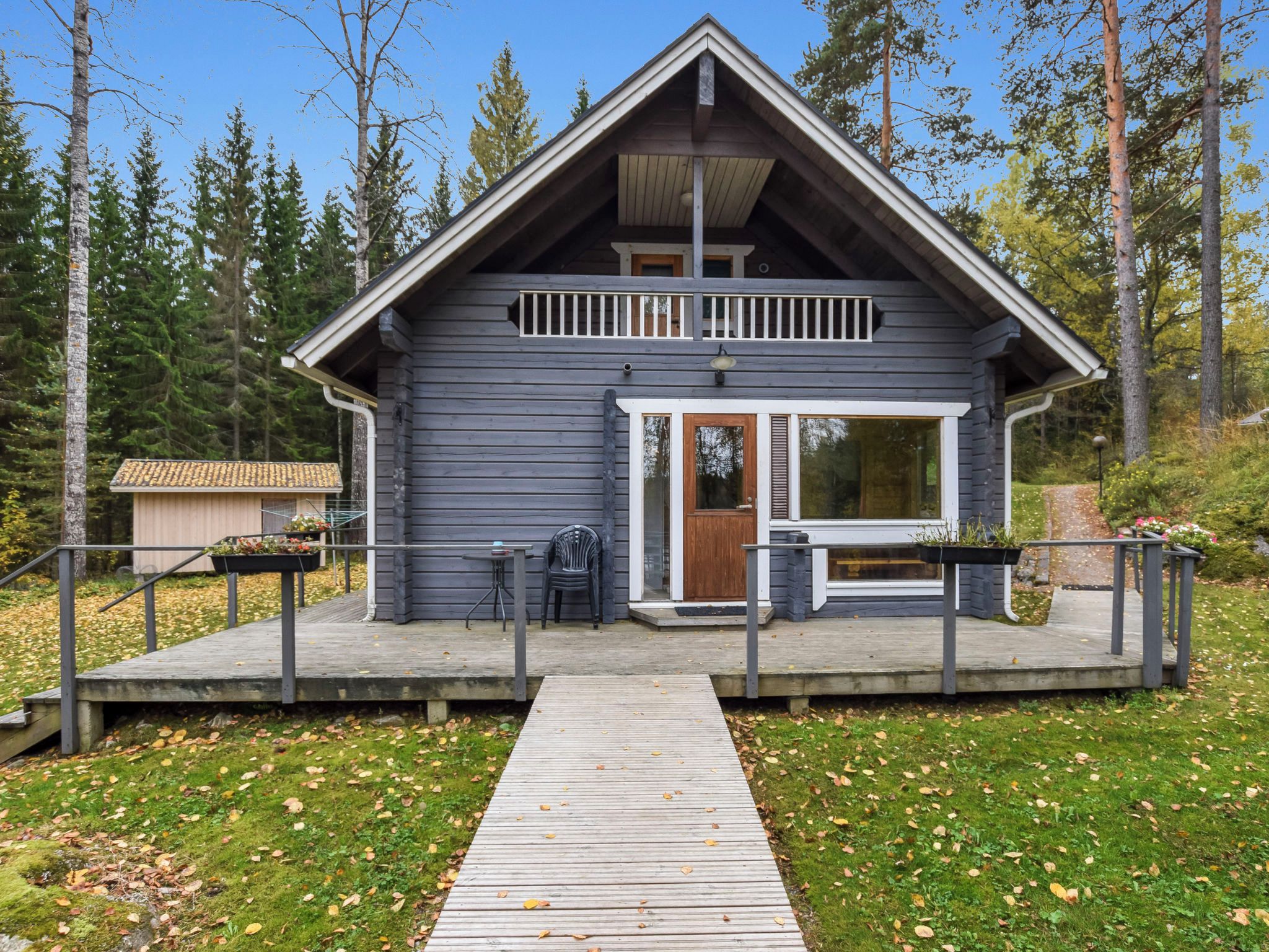 Une cabane dotée d’une terrasse en bois, d’un porche abrité et d’un petit espace extérieur aménagé pour s’asseoir.