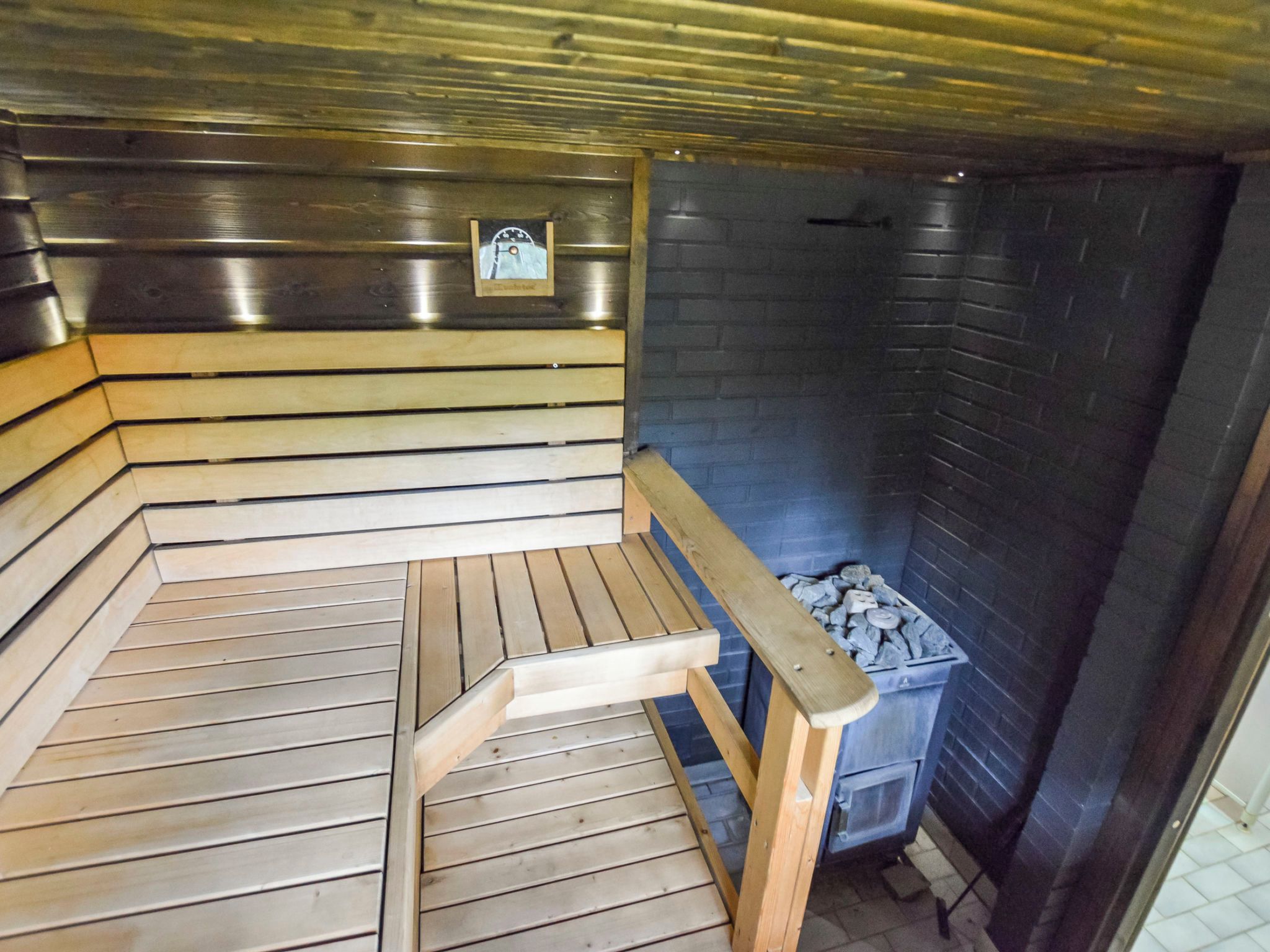 A sauna with wooden benches and a stone wall.