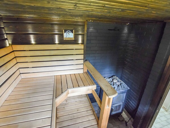 A sauna with wooden benches and a stone wall.