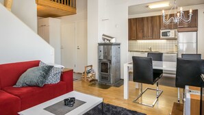 A modern apartment with a red sofa, a dining area, a kitchen, and a fireplace.