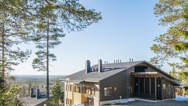 A modern lodge with a sloped roof, large windows, and a covered porch.
